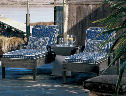 Traditional blue prints by Laura Ashley add color to these weather wood framed chaise lounges.